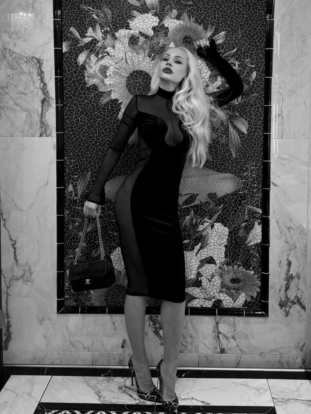 Against a mosaic wall, dressed in black